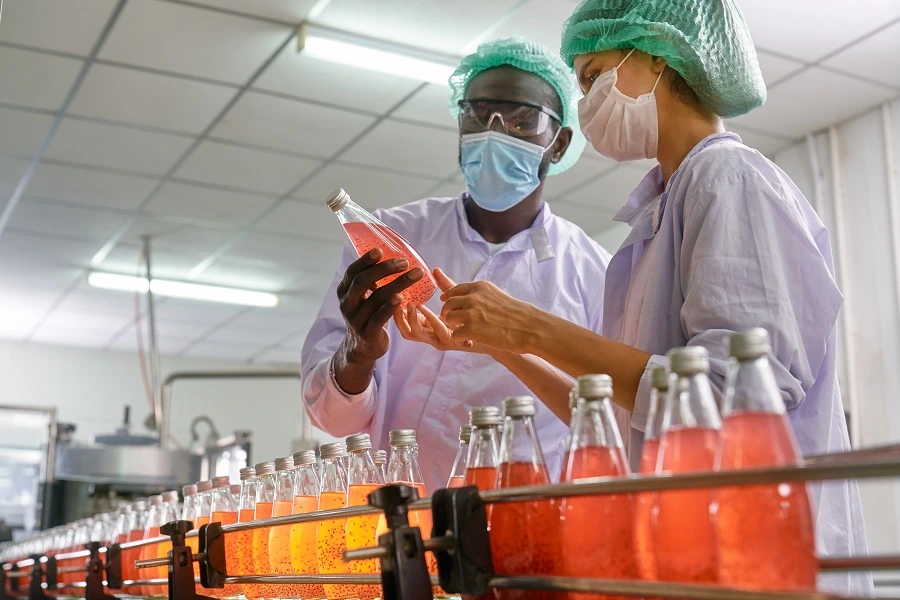 male and female scientists checking liquid juices in factory